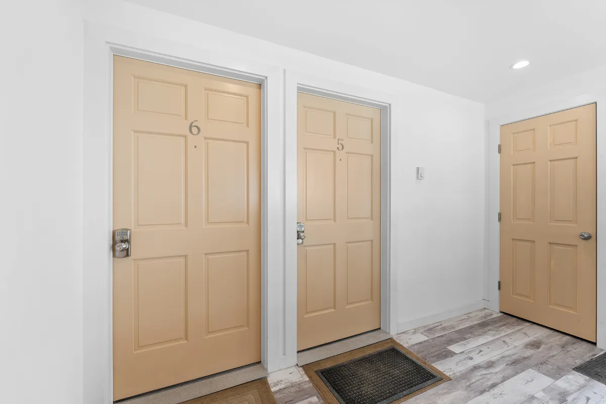 A focused view of the condo's entryway, highlighting doors labeled 5 and 6 with welcome mats. The neutral, inviting scene emphasizes the ease of access, setting the stage for arriving home with your pet after a day outside.