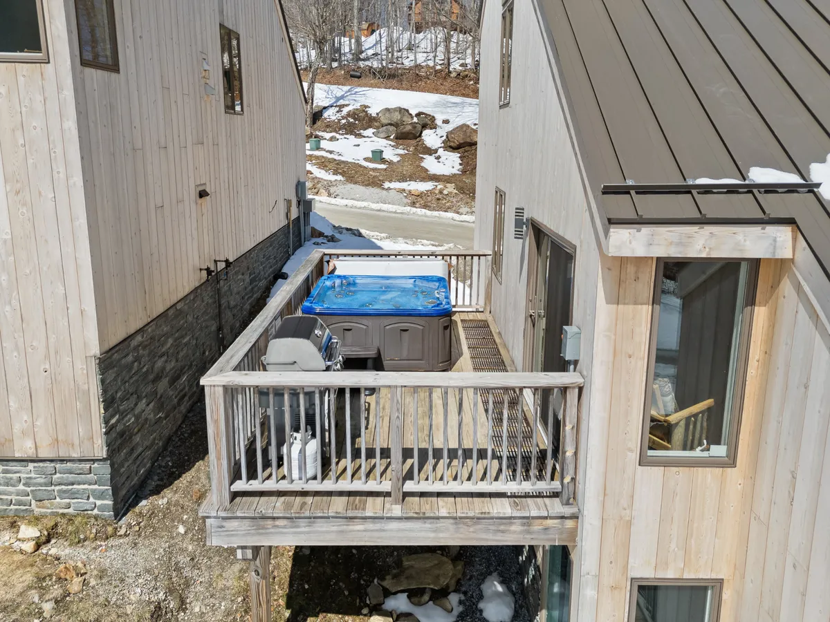 A private deck with a bubbling hot tub, a BBQ grill, and views of the surrounding landscape. The setup is perfect for relaxing after a day of adventure, offering seamless indoor-outdoor living and opportunities for al fresco dining or stargazing.