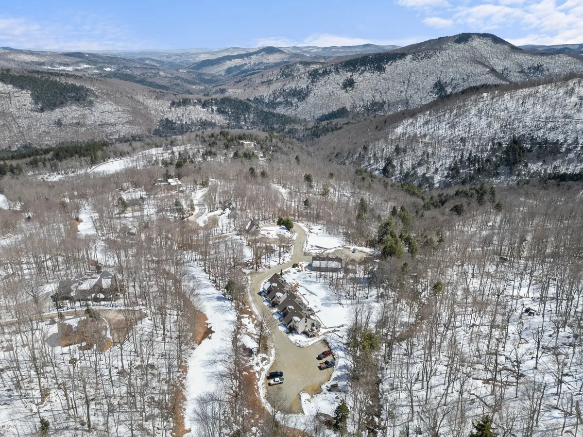 A sweeping view of snow-clad mountains, frosted trees, and scattered homes, capturing Killington’s winter wonderland. The image suggests opportunities for skiing, snowshoeing, and soaking in breathtaking mountain vistas.