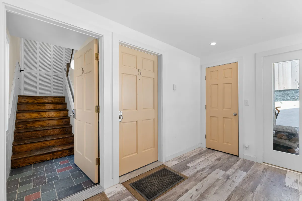This interior view focuses on a staircase and hallway with visible flooring and doors, suggesting the flow from entry into the heart of the home. The inviting mood and open layout encourage easy movement for guests with gear in tow.
