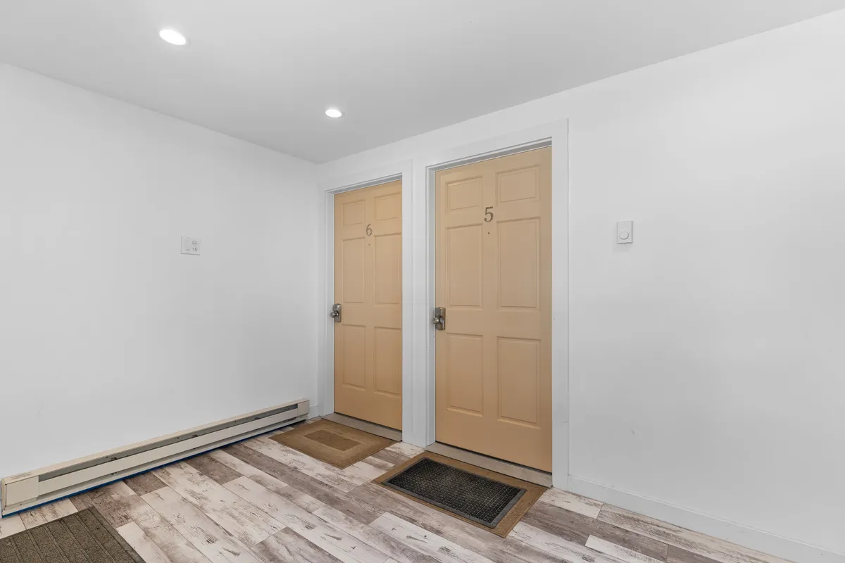 A hallway scene with prominent doors labeled 5 and 6 and welcome mats, suggesting the first point of contact for guests as they arrive. The clean and practical design emphasizes ease of entry and a welcoming atmosphere.