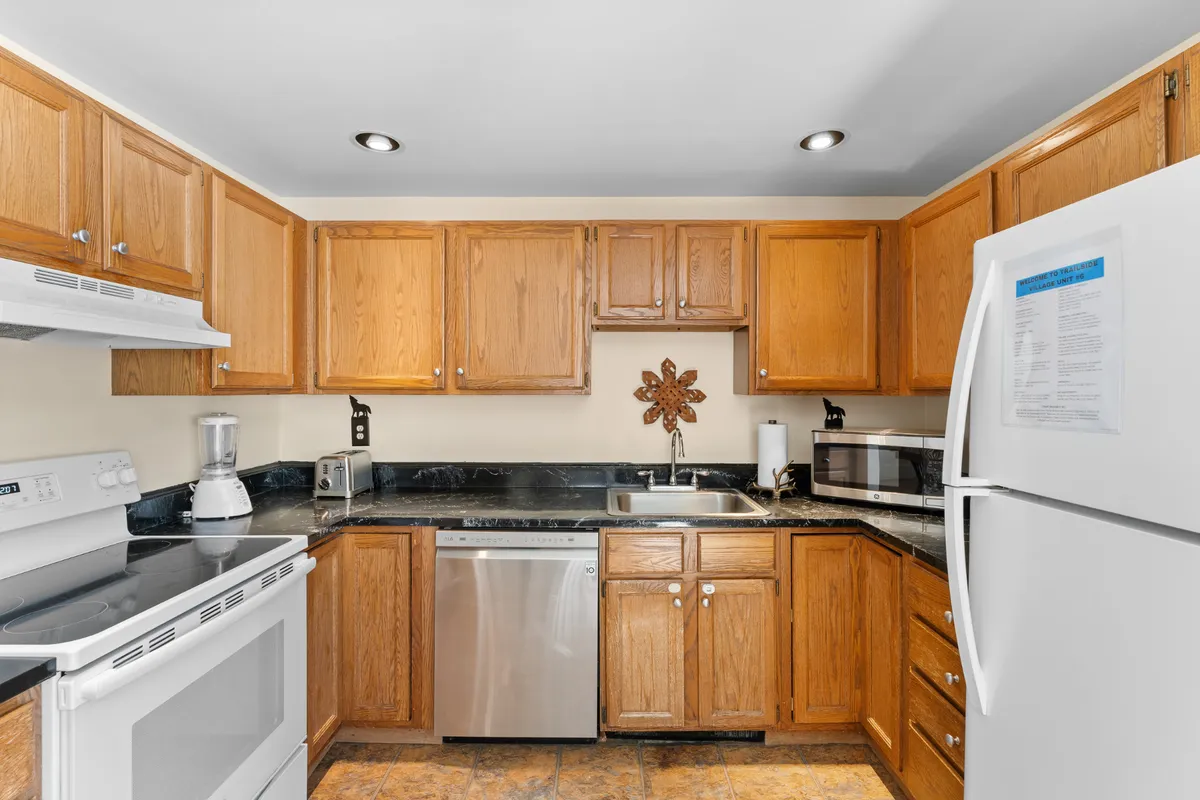 A welcoming kitchen scene featuring a kitchen countertop with wooden cabinets, black appliances, and a decorative wall piece. The space is clearly set up for meal prep, with all essential appliances and ample workspace visible, reflecting a modern and practical cooking area ideal for both casual and home chefs.